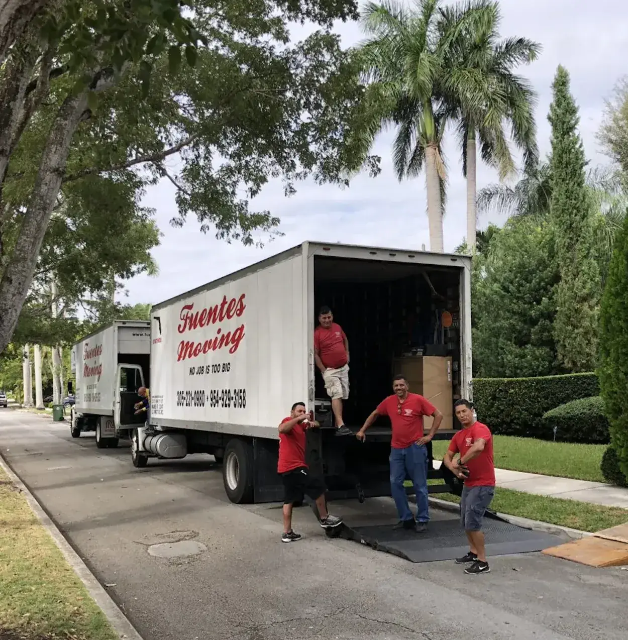 Fuentes Moving crew in red shirts unloading a branded moving truck on a Miami street