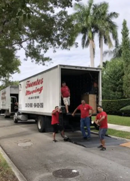 Fuentes Moving movers in red shirts working at the back of a branded box truck
