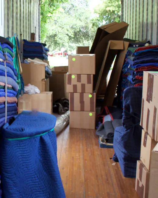 Inside a moving truck with blue moving pads and stacked boxes