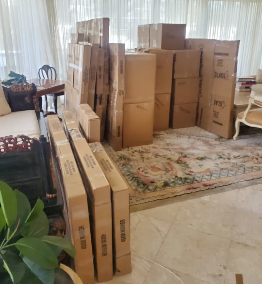 Boxes and wardrobe cartons stacked in a living room ready to move